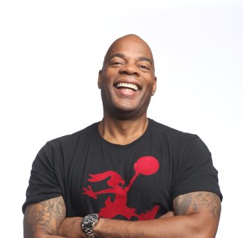 Alonzo Bodden smiling with arms crossed in black t-shirt