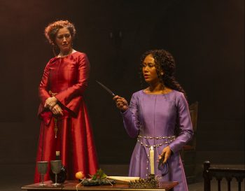 A woman looks at a knife while a queen watches from behind