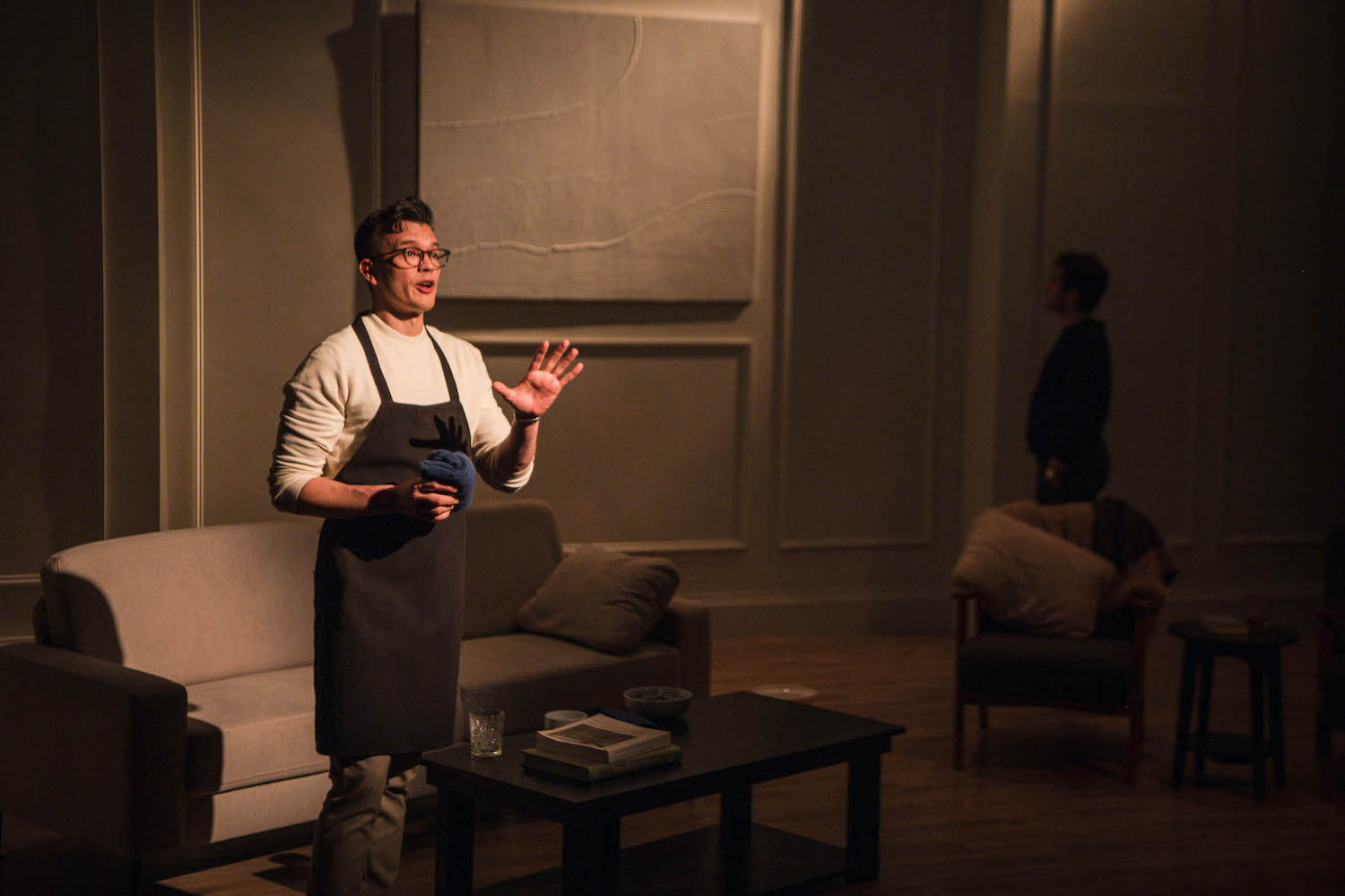 A man stands in the dark wearing a painters apron.