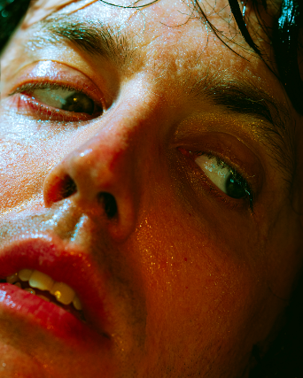 A close-up of a persons face, showing sweaty skin, slightly parted lips, and eyes looking to the side.